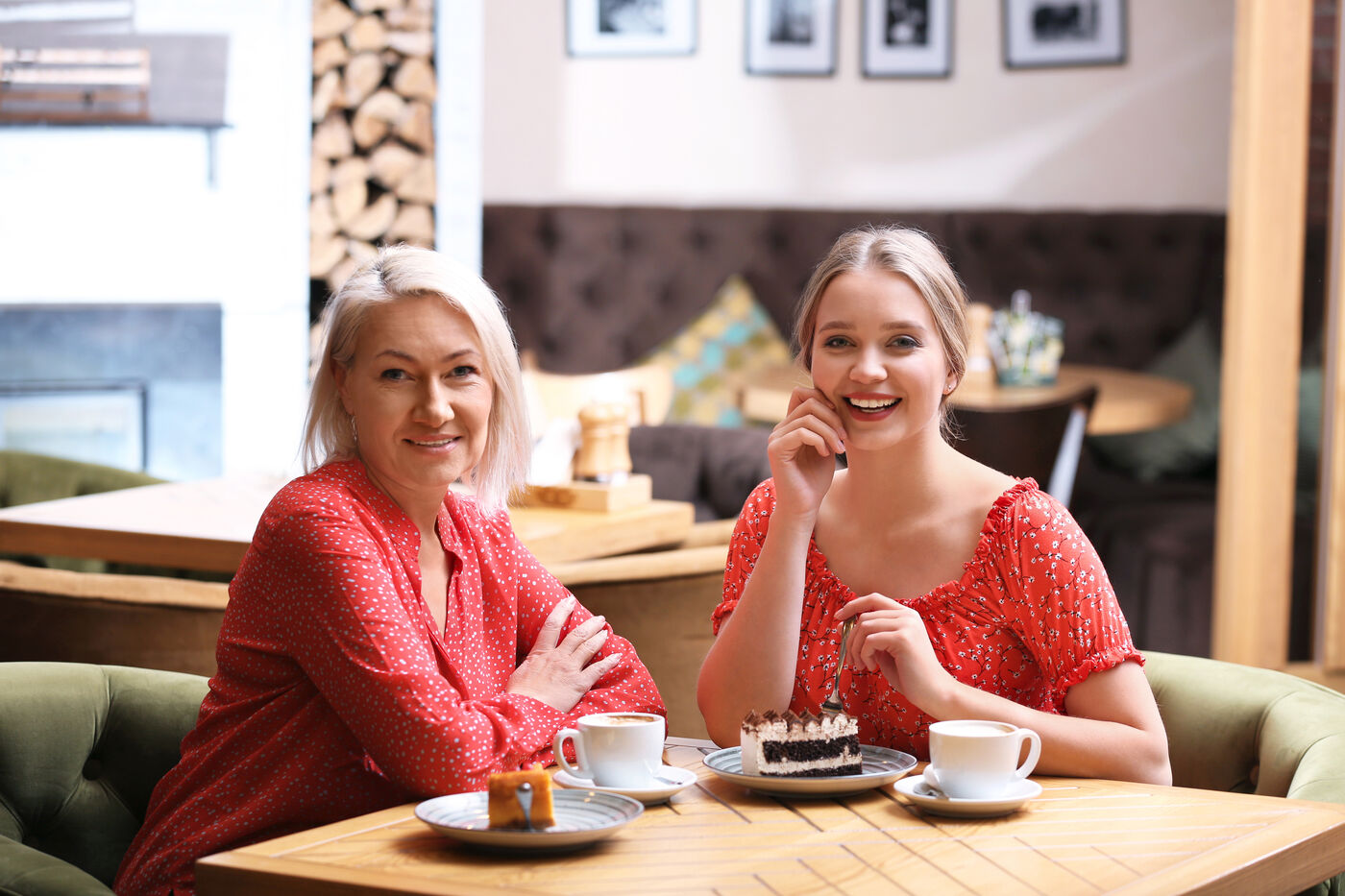 Two smiling women sharing coffee and cake at a cozy café