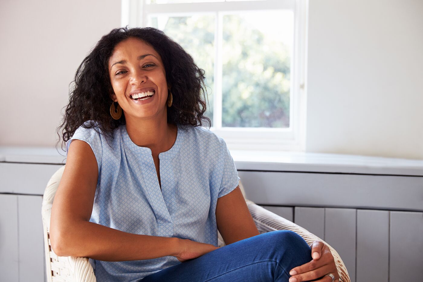 Woman with curly hair laughing in a sunny room